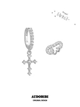 Angel-wing stud and cross hoop earring on a white background.