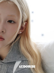 Angel-wing studs and cross hoop earrings, worn with other jewelry in a model portrait.