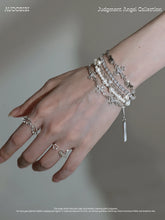 Layered bead bracelet with a hanging charm, worn with other jewelry in a model portrait.