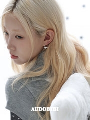 Mini wing-and-star hoop earrings, worn with other jewelry in a model portrait.