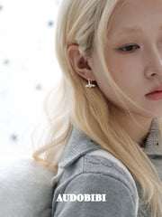 Mini wing-and-star hoop earrings, worn with other jewelry in a model portrait.
