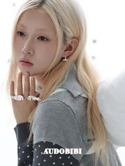 Mini wing-and-star hoop earrings, worn with other jewelry in a model portrait.