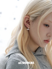Mini wing-and-star hoop earrings, worn with other jewelry in a model portrait.