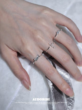 Cross and wing rings, shown on the hand or wrist with other jewelry.