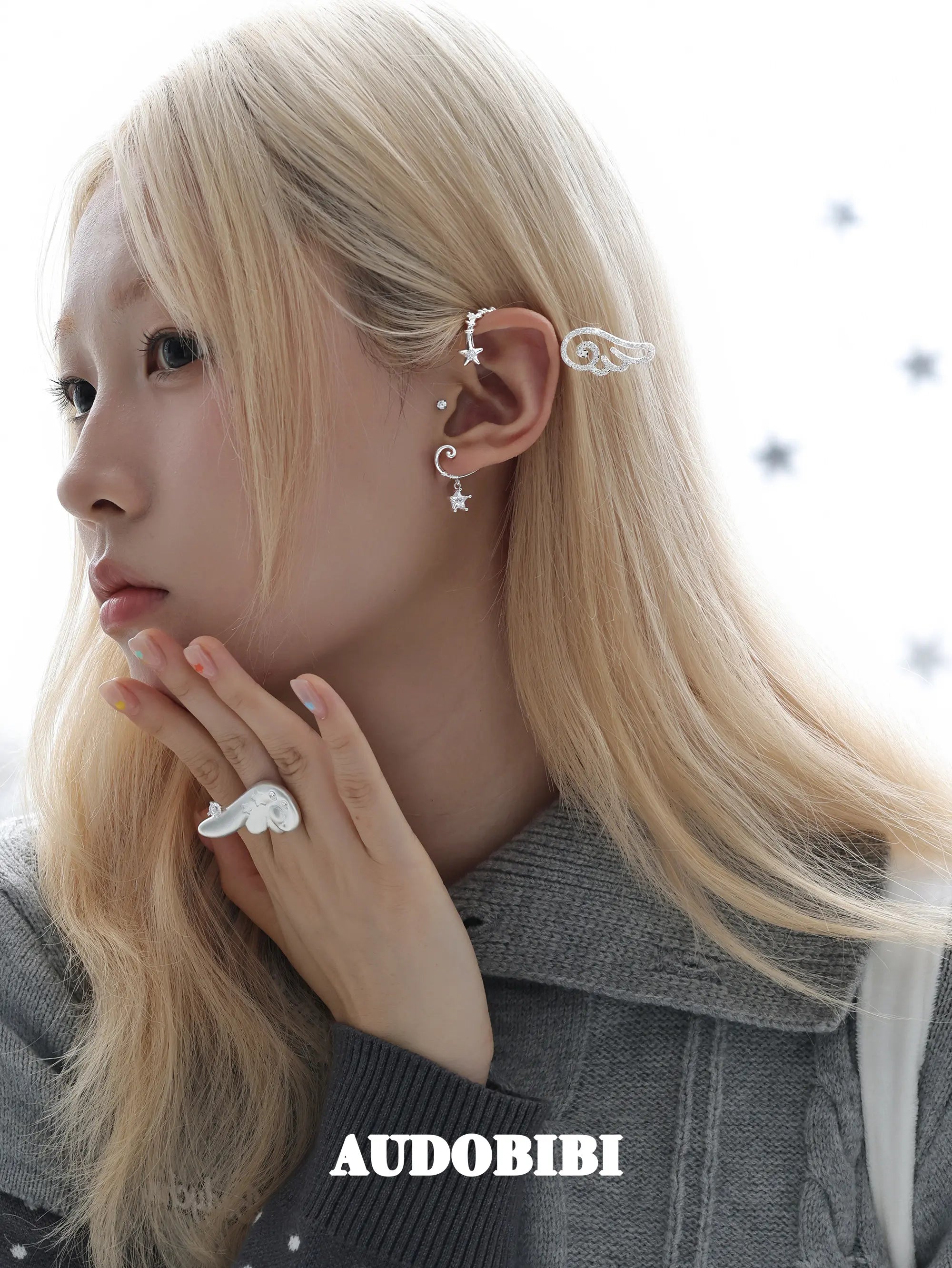 Large openwork wing ear cuff, worn with other jewelry in a model portrait.