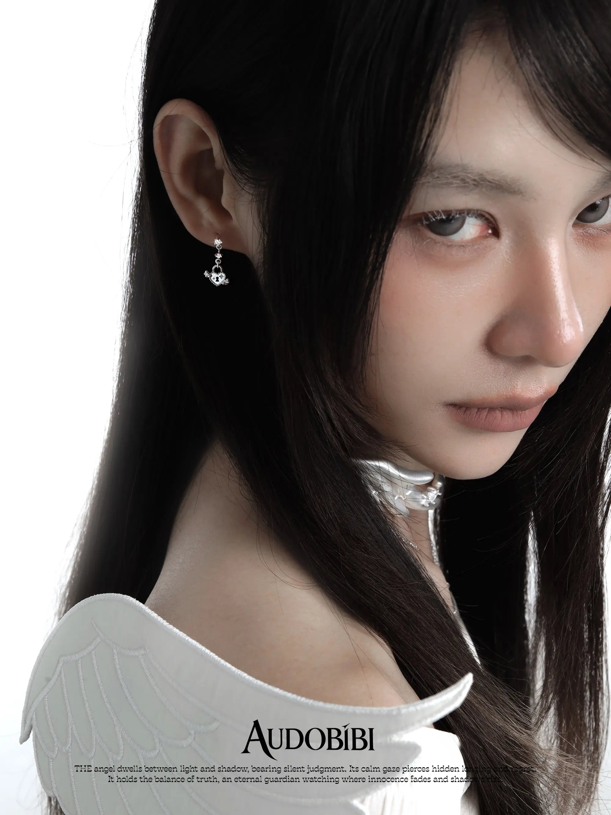 Key and heart-lock earrings, worn with other jewelry in a model portrait.