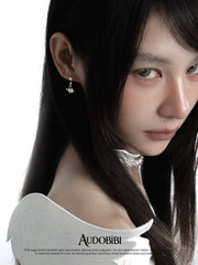 Key and heart-lock earrings, worn with other jewelry in a model portrait.