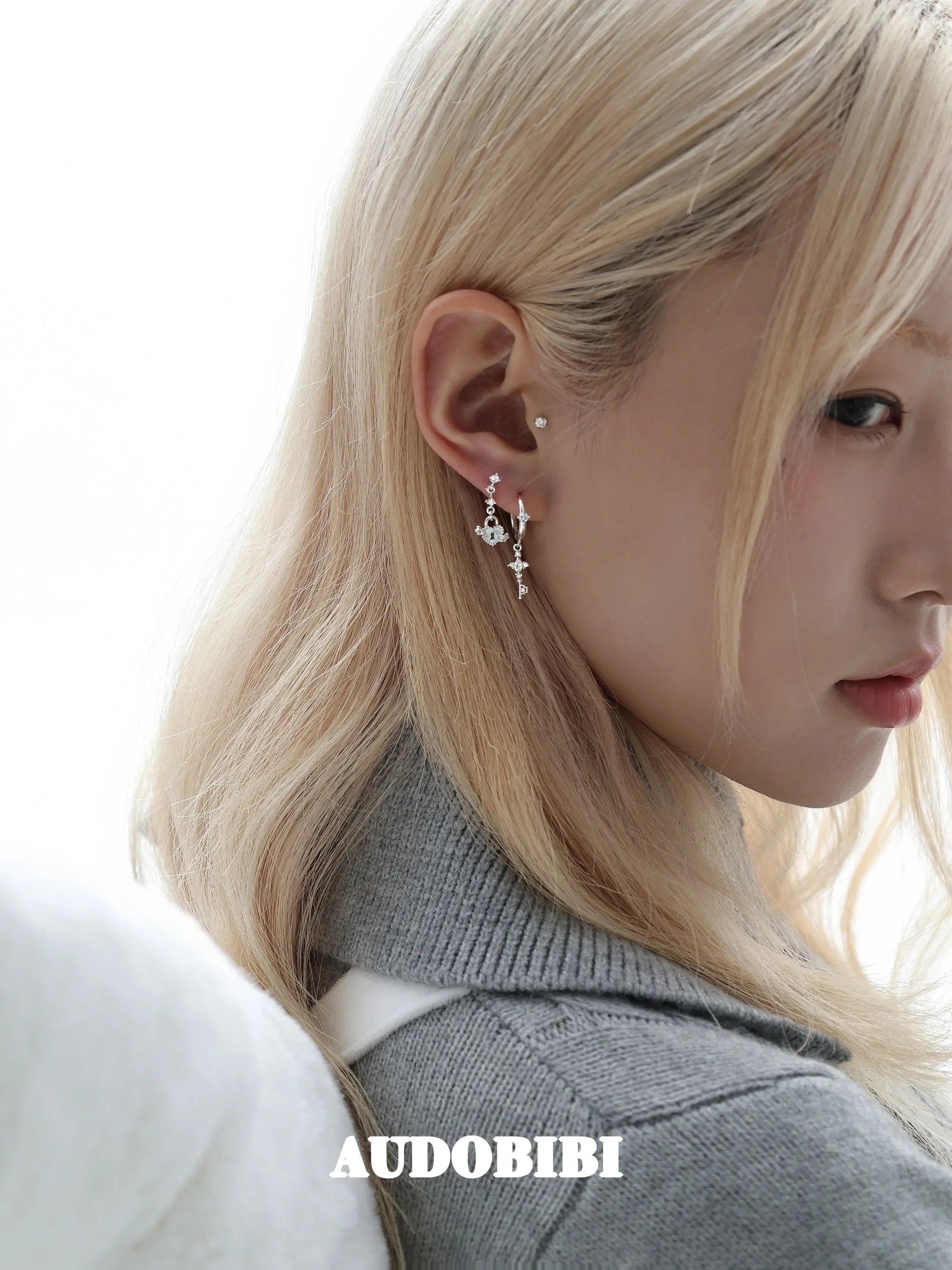 Key and heart-lock earrings, shown in a close-up of the ear.