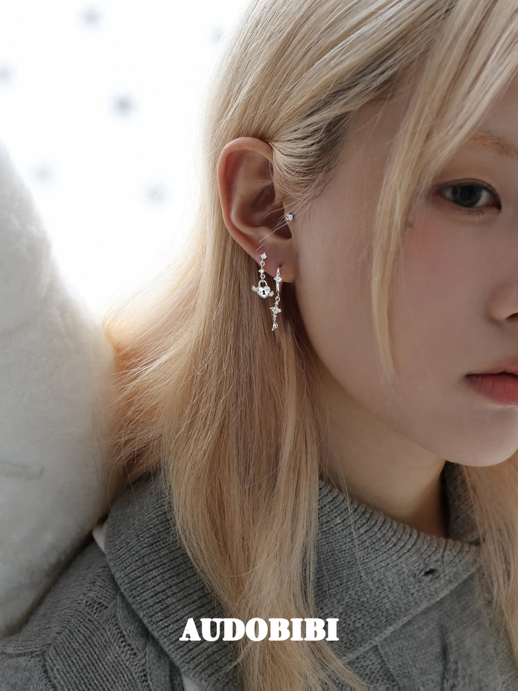 Key and heart-lock earrings, shown in a close-up of the ear.