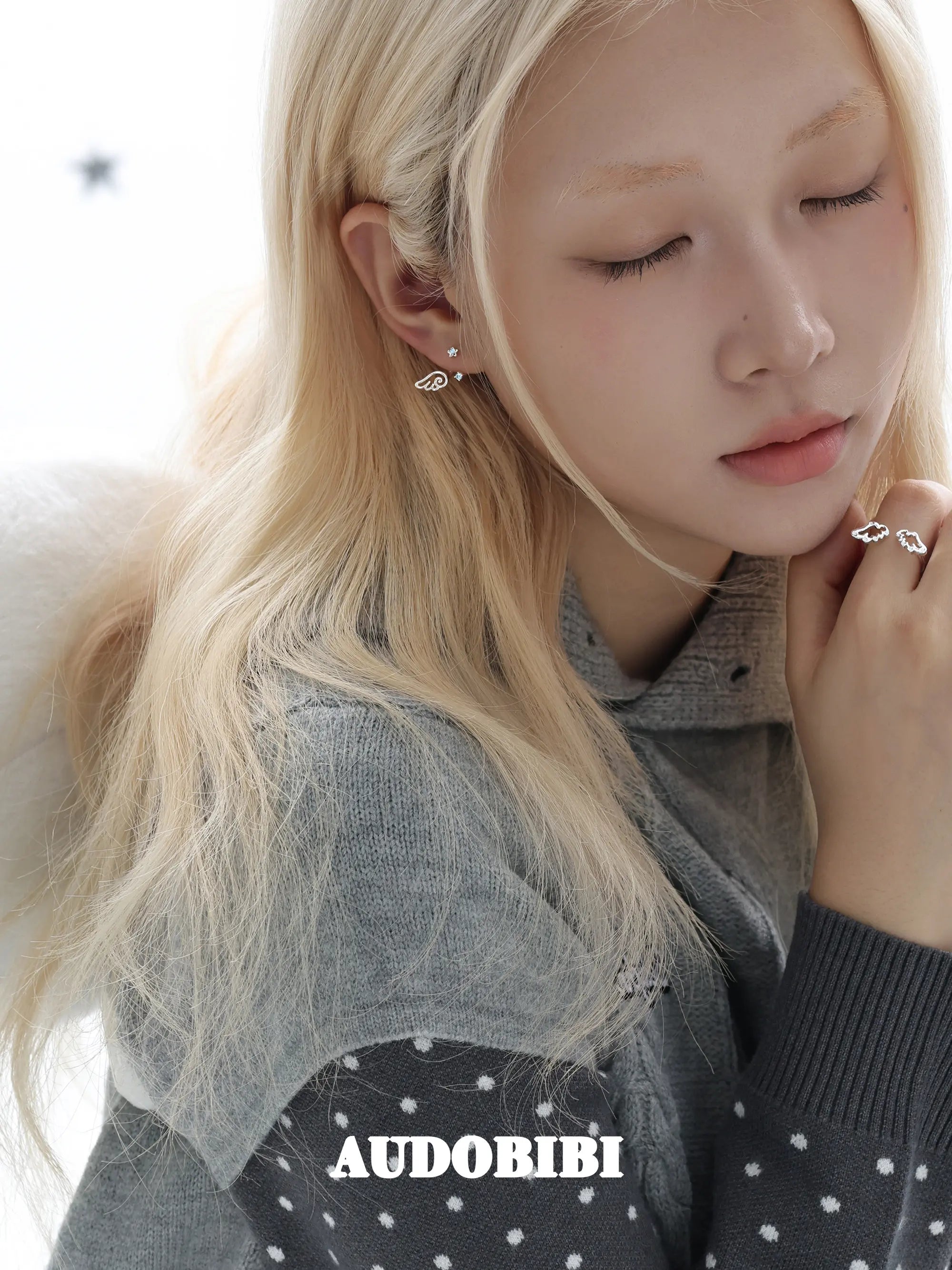 Open ring with two outlined wings, worn with other jewelry in a model portrait.
