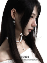 Winged-key hoop earrings, worn with other jewelry in a model portrait.