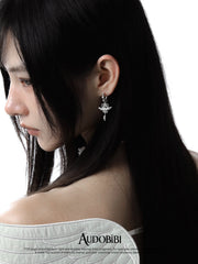 Winged-key hoop earrings, worn with other jewelry in a model portrait.