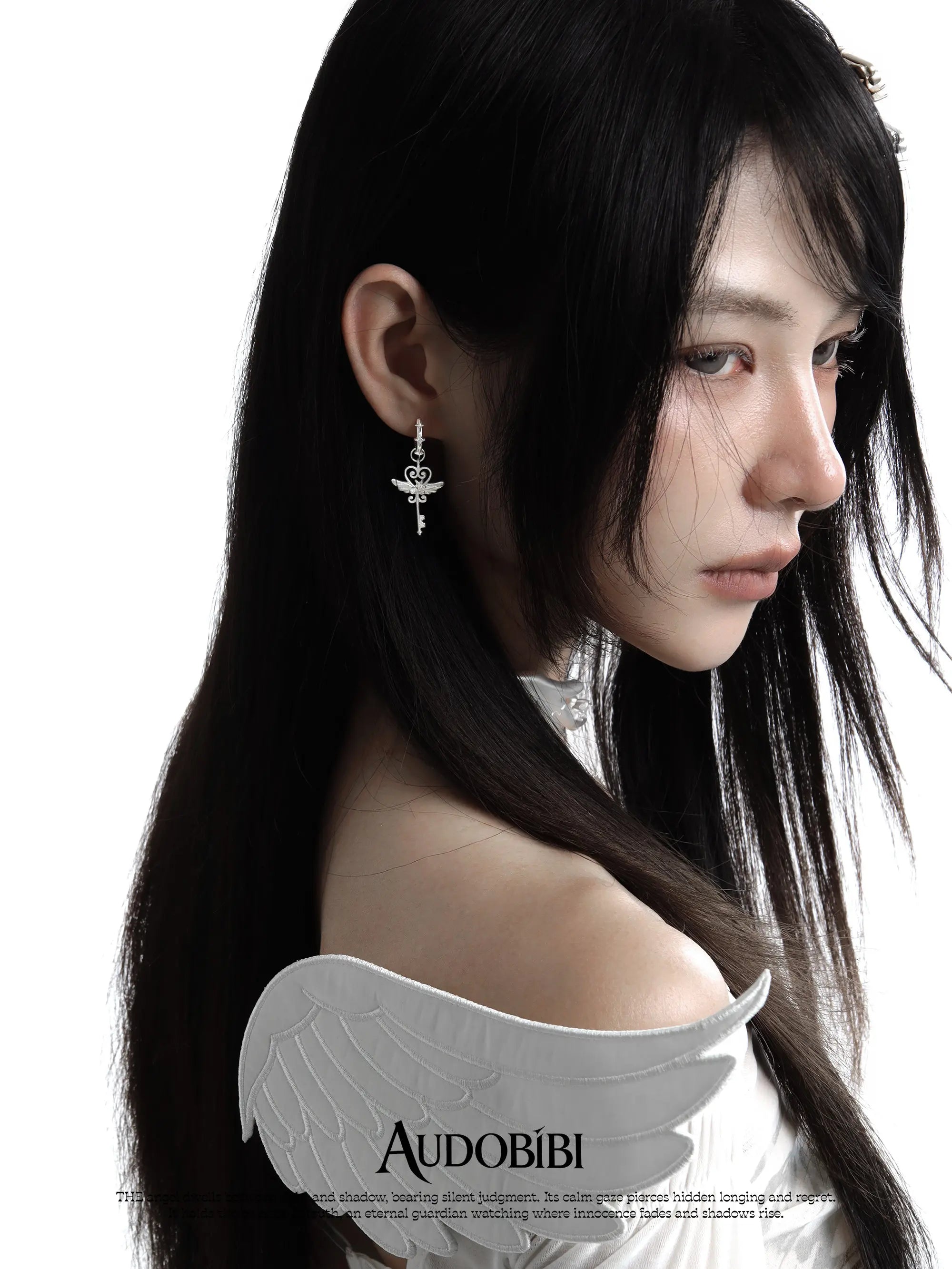 Winged-key hoop earrings, worn with other jewelry in a model portrait.