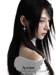 Winged-key hoop earrings, worn with other jewelry in a model portrait.