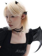 Black bat-wing ear cuff, worn with other jewelry in a model portrait.