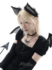 Black bat-wing pendant necklace, worn with other jewelry in a model portrait.