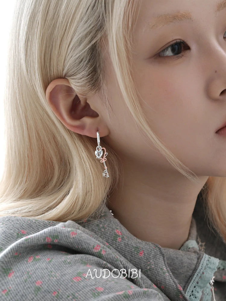 Lily Dreamlock Asymmetric Heart-Key Drop Earrings, shown worn by a model.
