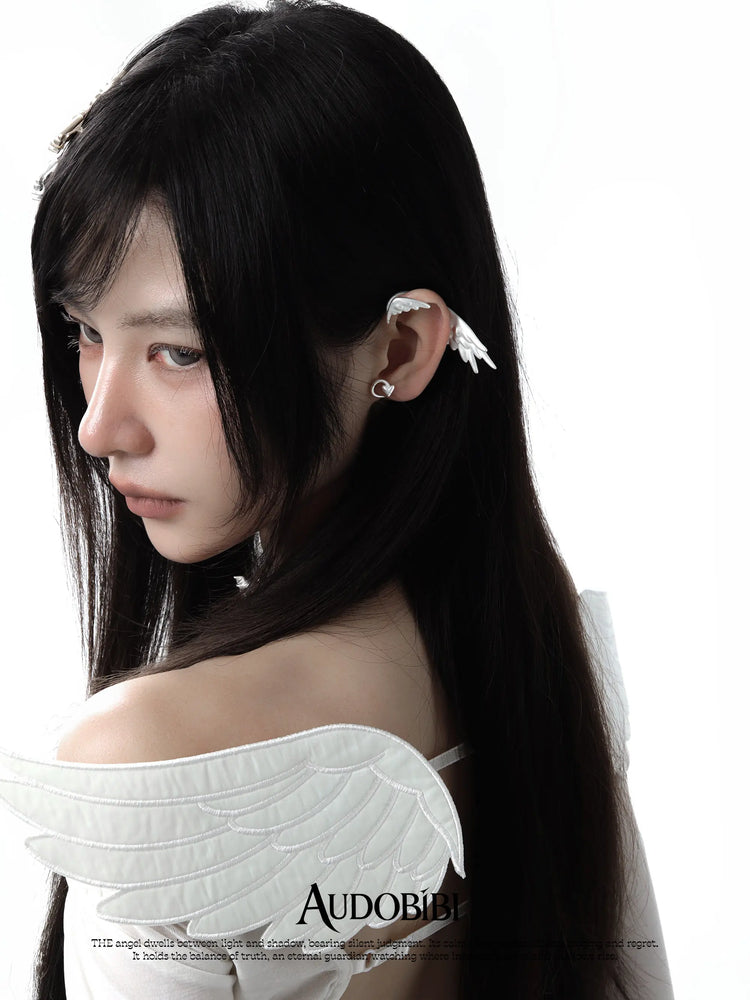 Wing ear cuff, worn with other jewelry in a model portrait.