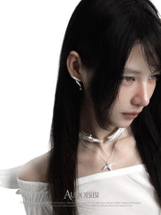 Wing choker with a draped chain, worn with other jewelry in a model portrait.