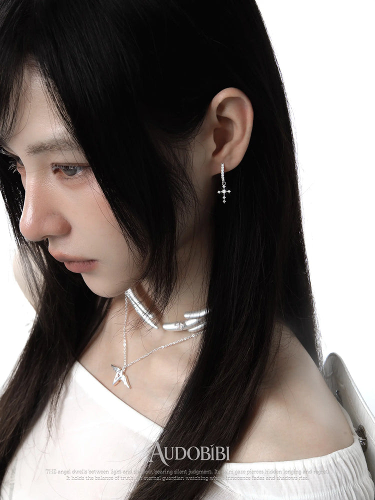 Wing choker with a draped chain, worn with other jewelry in a model portrait.