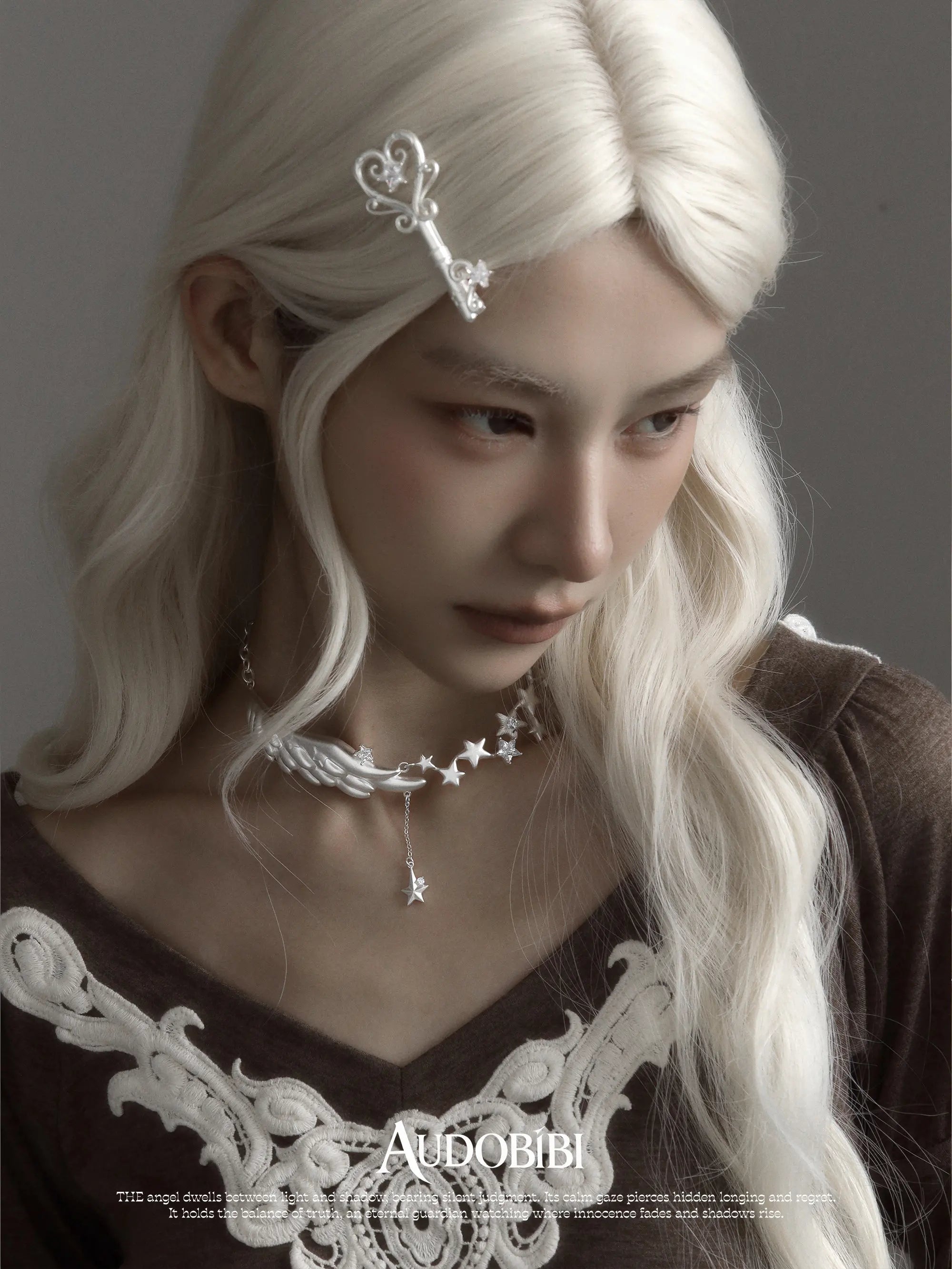 Wing-and-star necklace, worn with other jewelry in a model portrait.