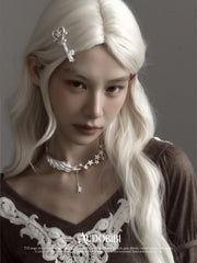 Wing-and-star necklace, worn with other jewelry in a model portrait.