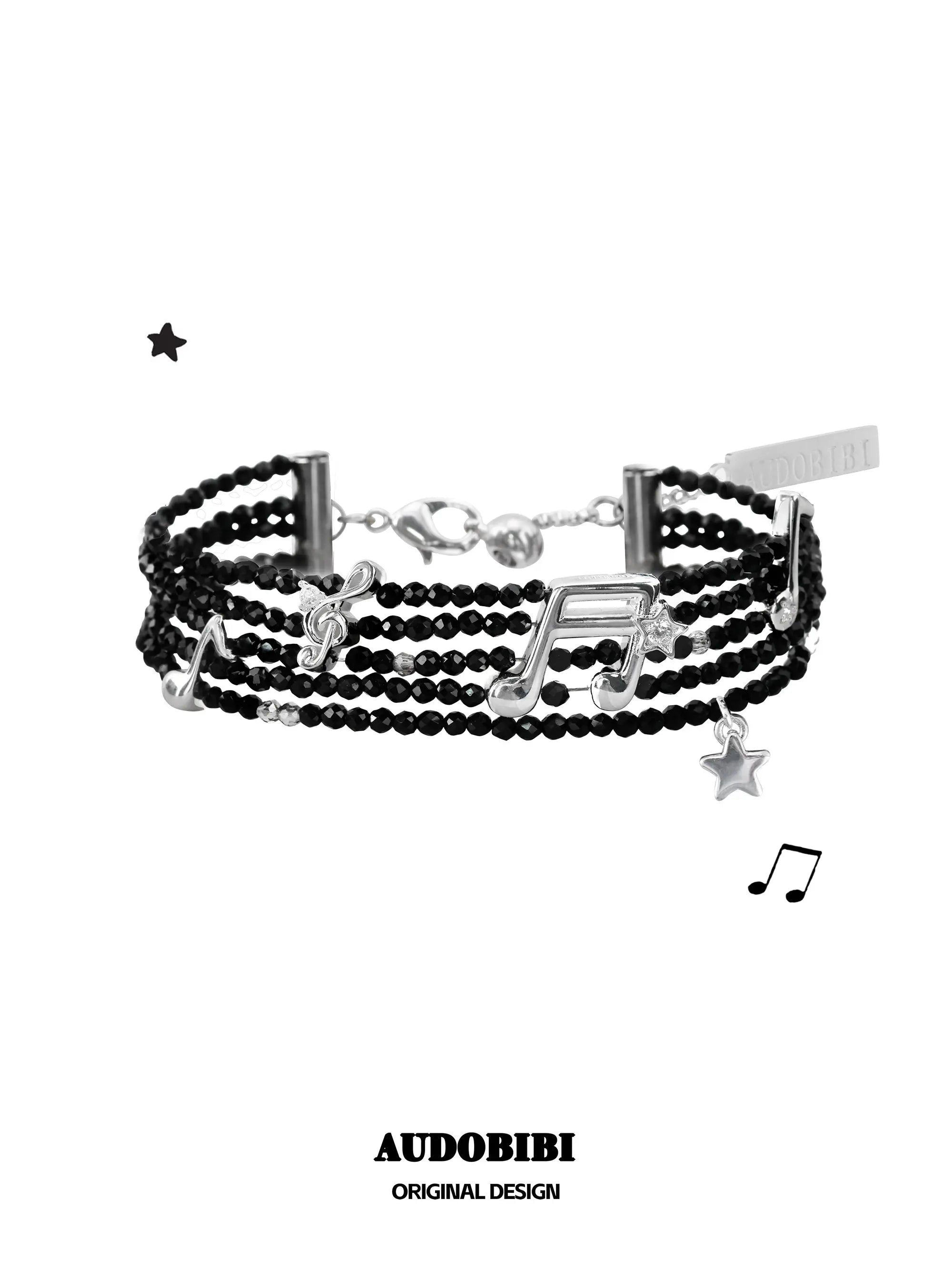 Multi-strand black bead bracelet with musical-note and star details.