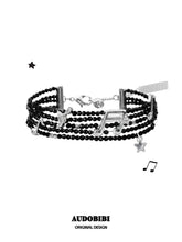 Multi-strand black bead bracelet with musical-note and star details.