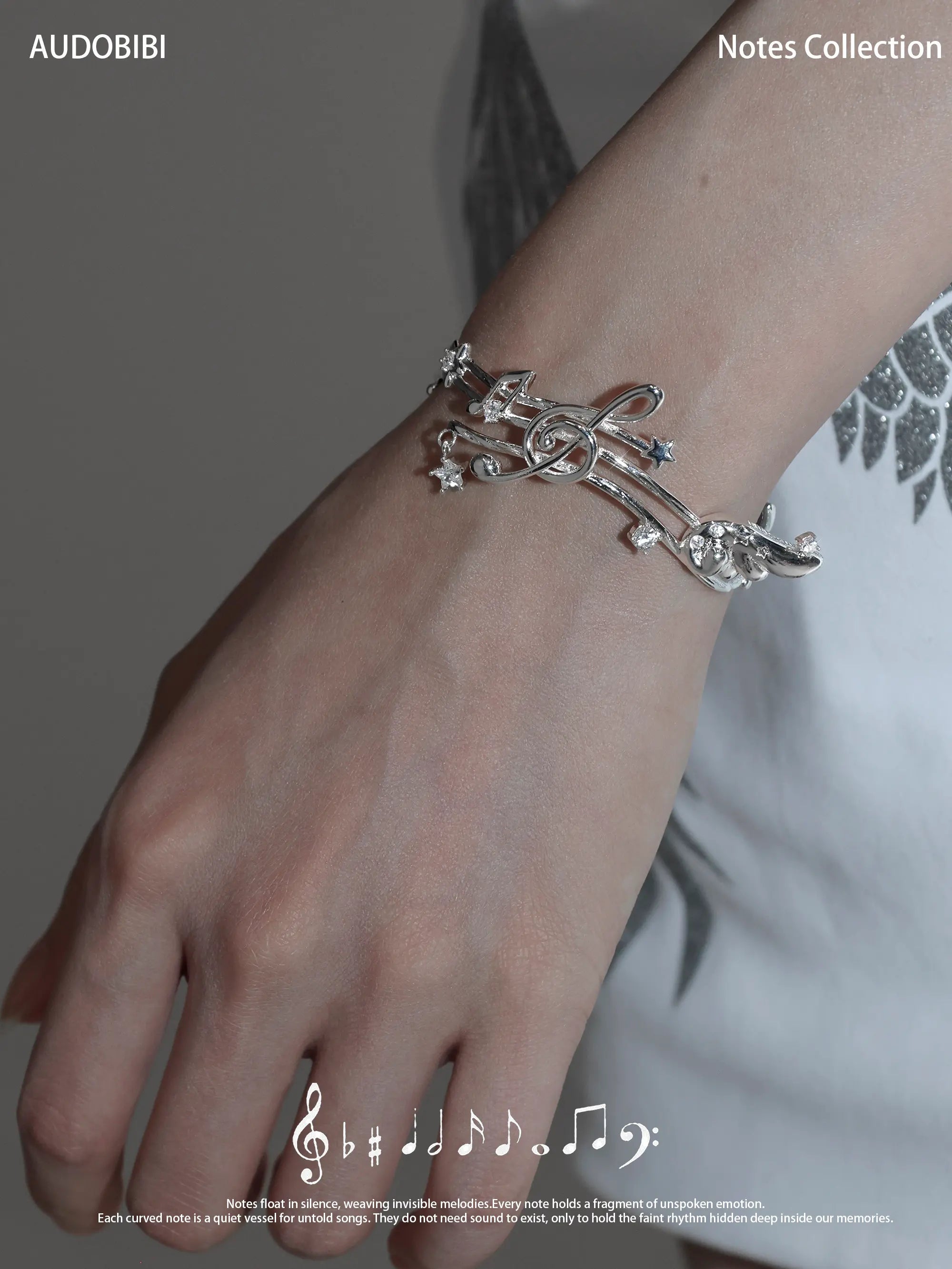 Musical-staff open bangle, shown on the hand or wrist with other jewelry.