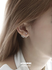 Star-and-wing stud earrings, shown in a close-up of the ear.