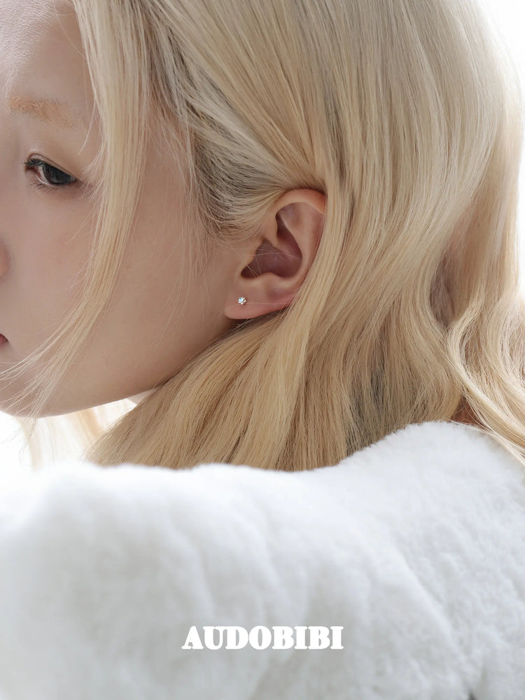 Star-and-wing stud earrings, shown in a close-up of the ear.