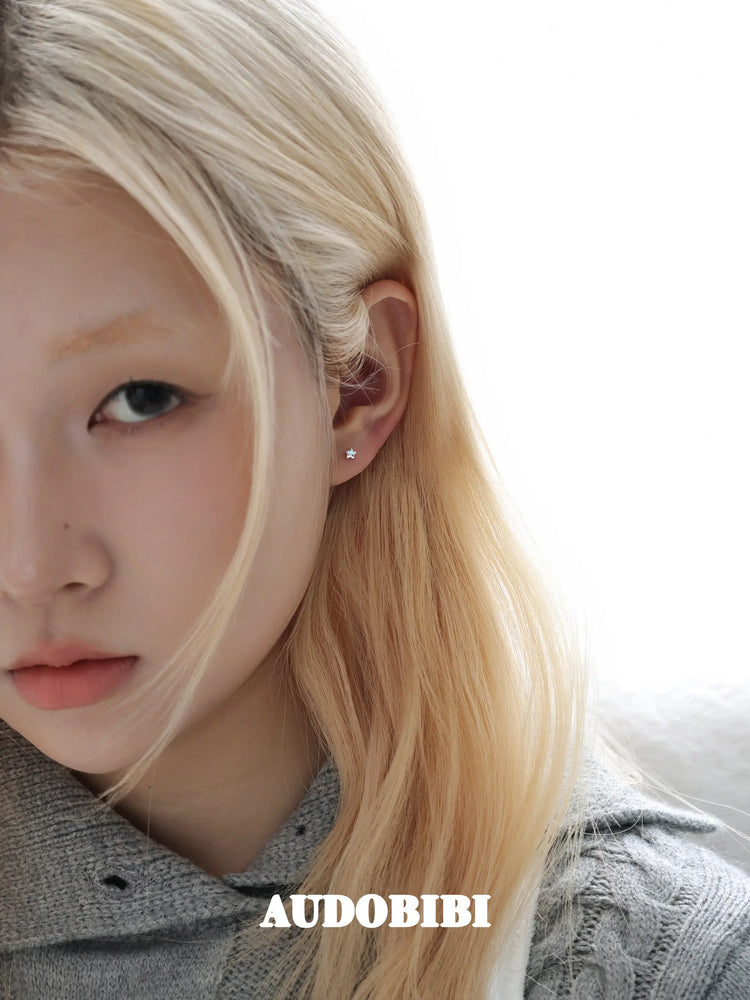 Star-and-wing stud earrings, worn with other jewelry in a model portrait.