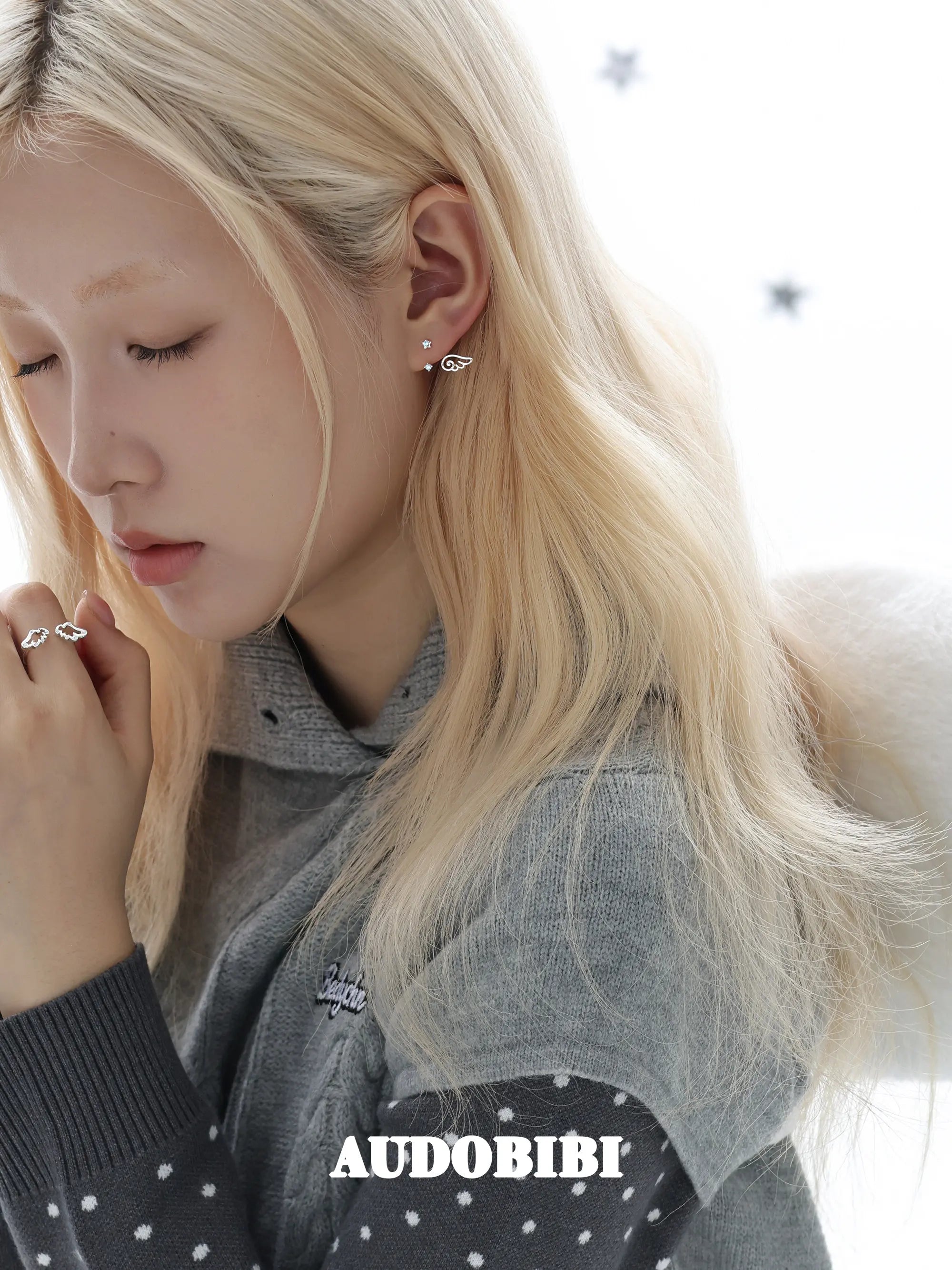 Star-and-wing stud earrings, worn with other jewelry in a model portrait.