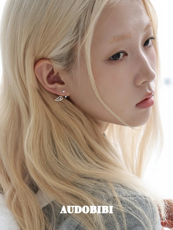 Star-and-wing stud earrings, worn with other jewelry in a model portrait.