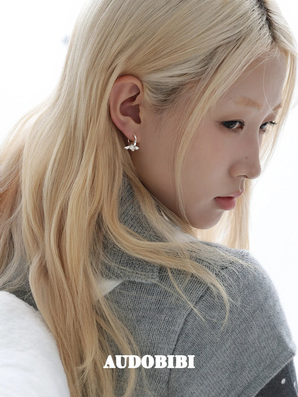 Mini wing-and-star hoop earrings, worn with other jewelry in a model portrait.
