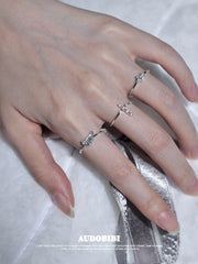Cross and wing rings, shown on the hand or wrist with other jewelry.