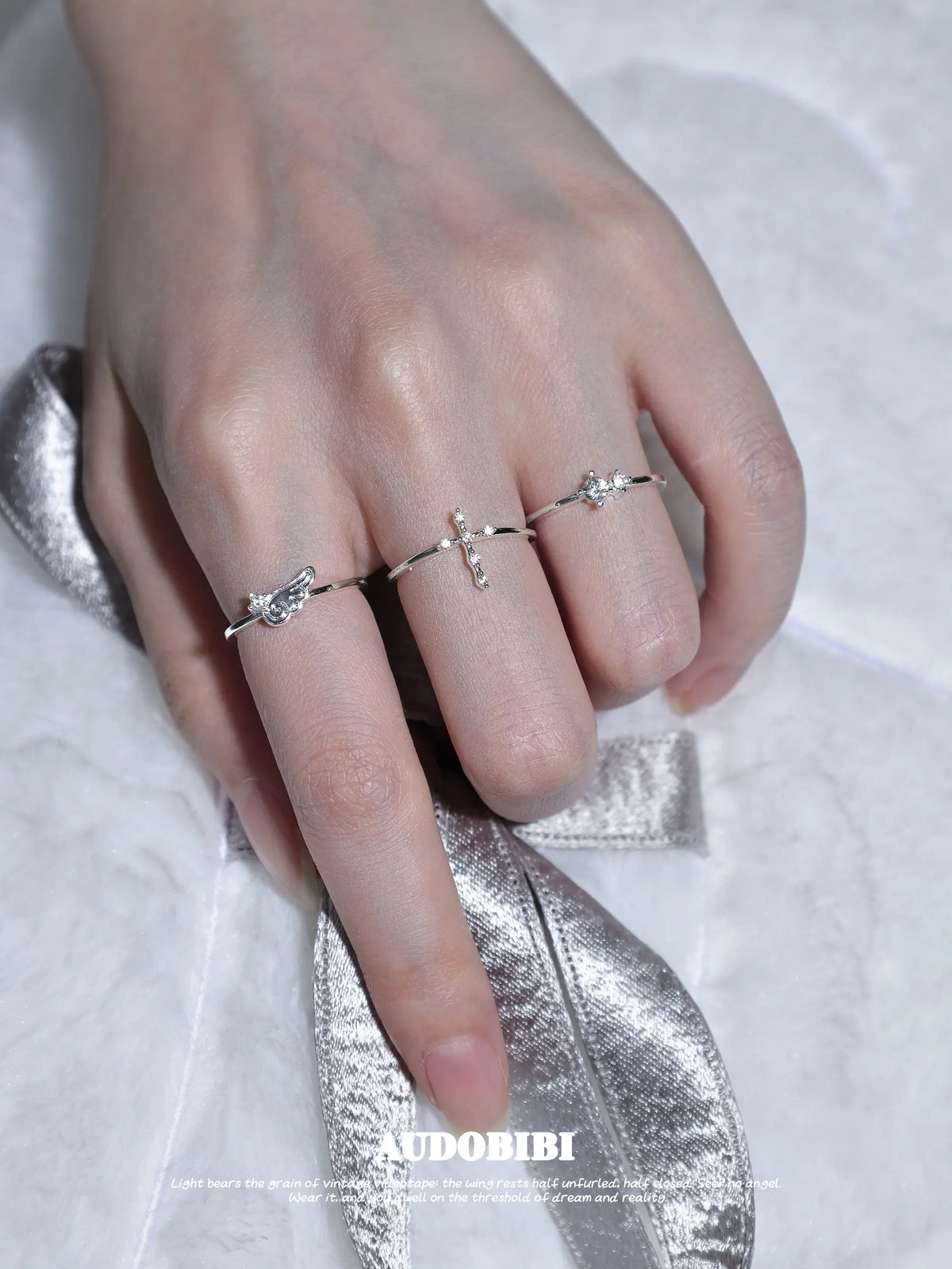 Cross and wing rings, shown on the hand or wrist with other jewelry.