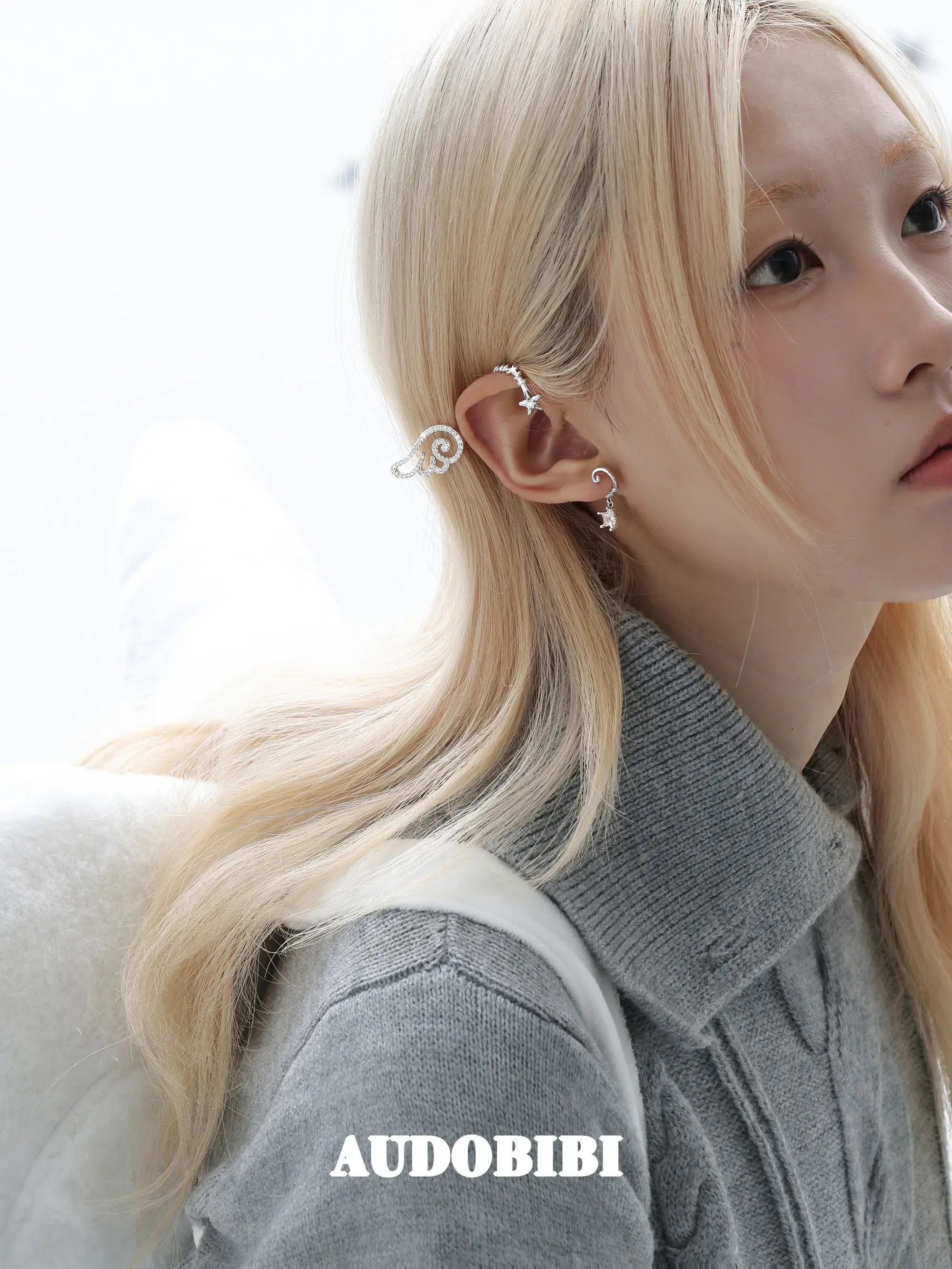 Large openwork wing ear cuff, worn with other jewelry in a model portrait.