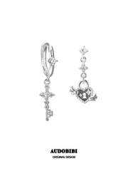 Key and winged heart-lock hoop earrings on a white background.