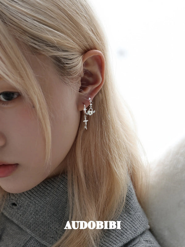 Key and heart-lock earrings, worn with other jewelry in a model portrait.