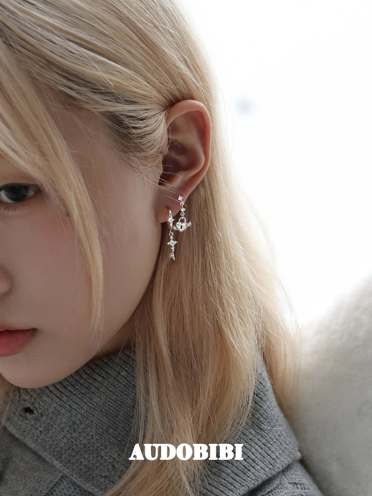 Key and heart-lock earrings, worn with other jewelry in a model portrait.