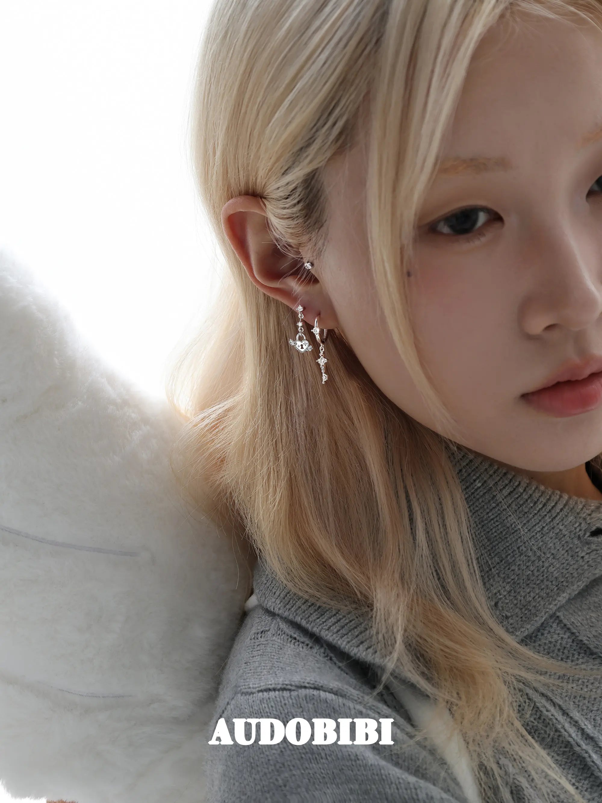 Key and heart-lock earrings, worn with other jewelry in a model portrait.