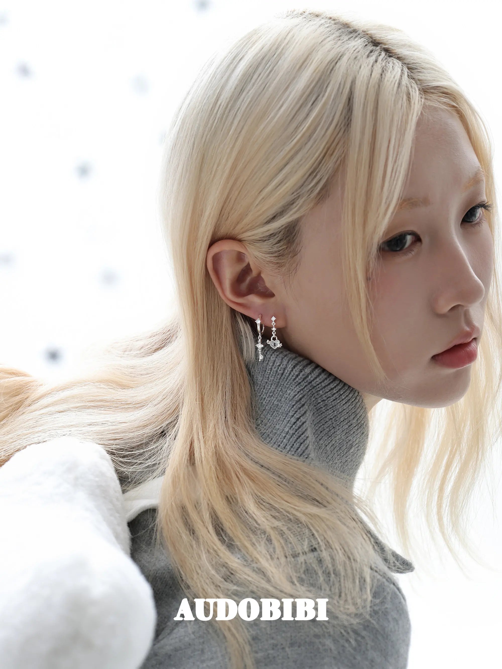 Key and heart-lock earrings, worn with other jewelry in a model portrait.
