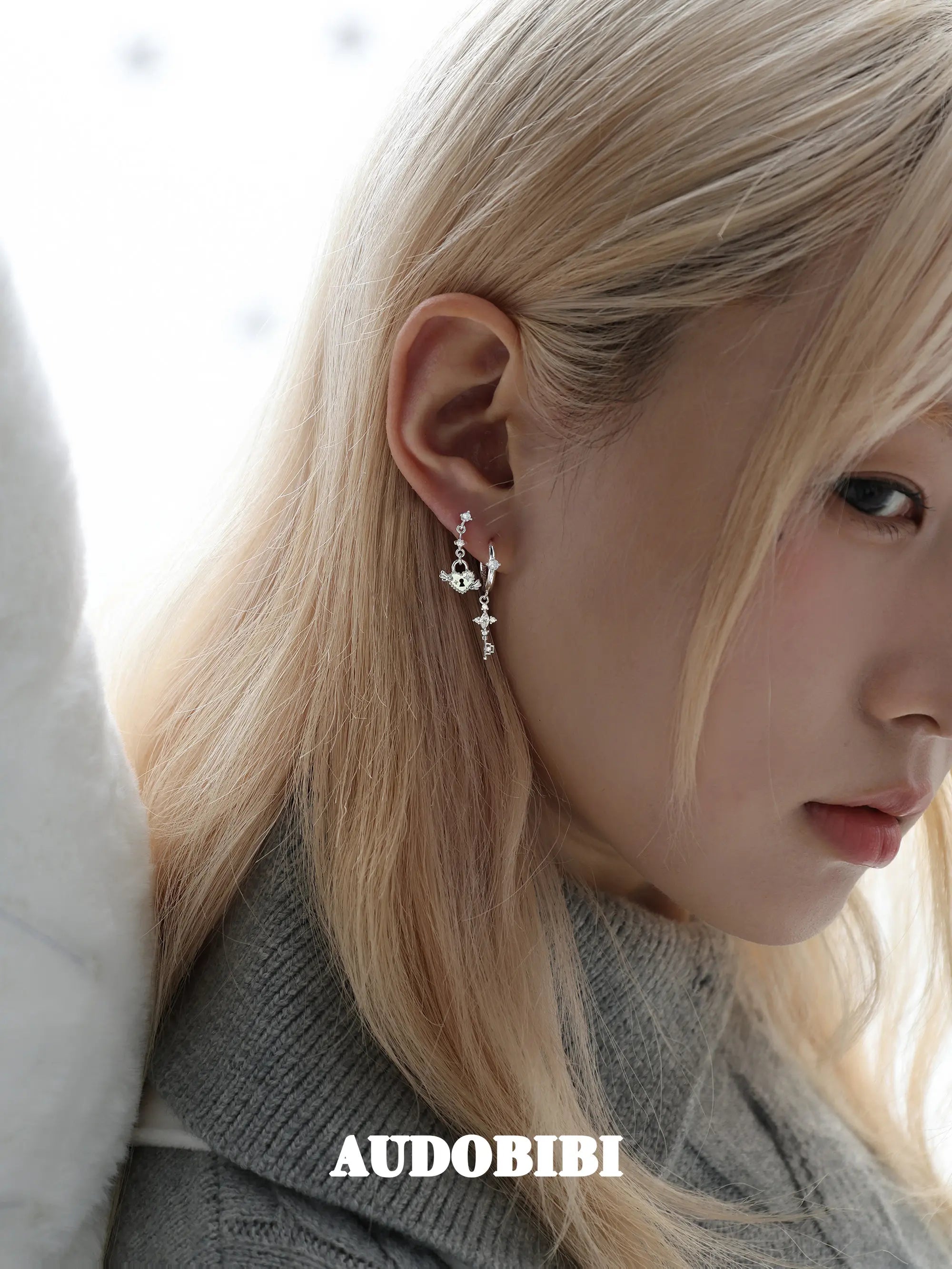 Key and heart-lock earrings, shown in a close-up of the ear.
