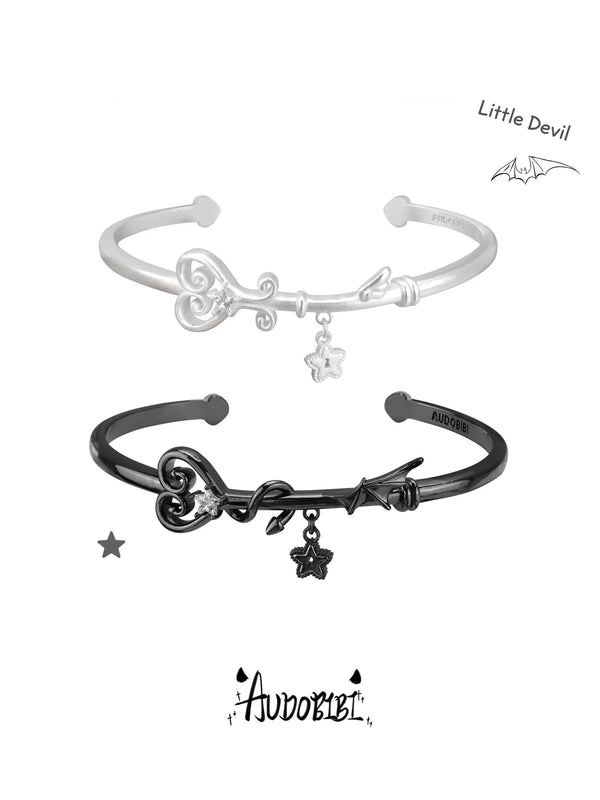 Silver-tone and black winged-key open bangles shown together.