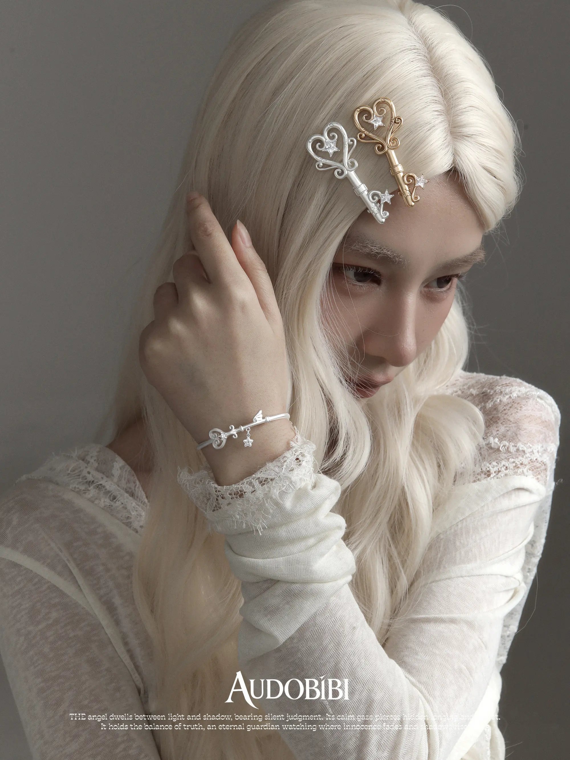 Winged-key open bracelet, worn with other jewelry in a model portrait.