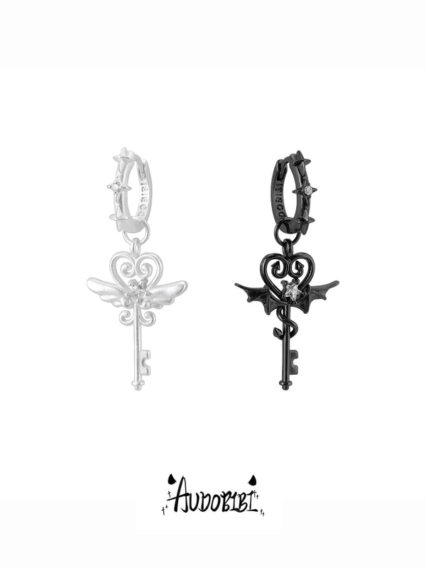 Silver-tone angel-key and black devil-key hoop earrings shown together.