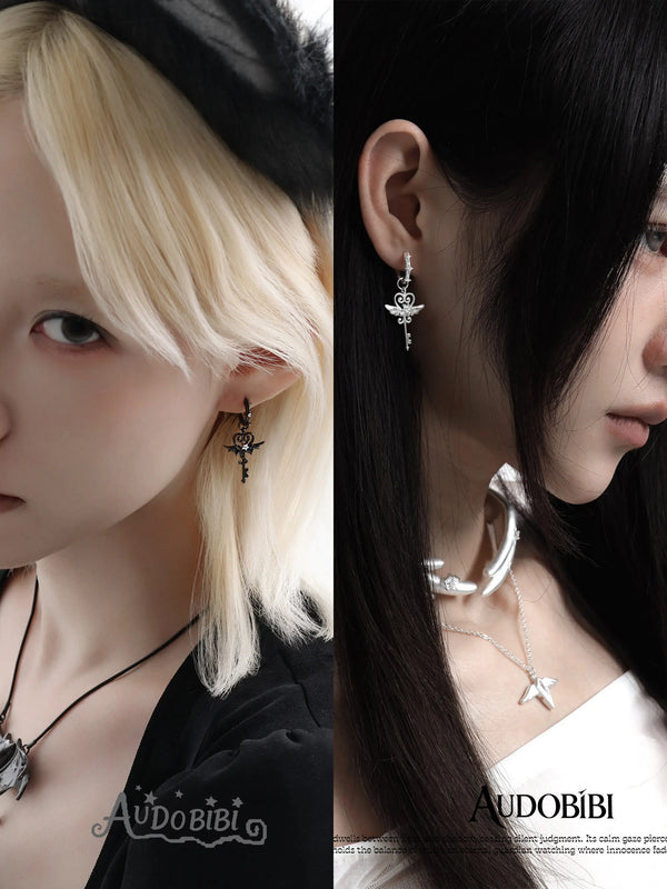 Winged-key hoop earrings, worn with other jewelry in a model portrait.