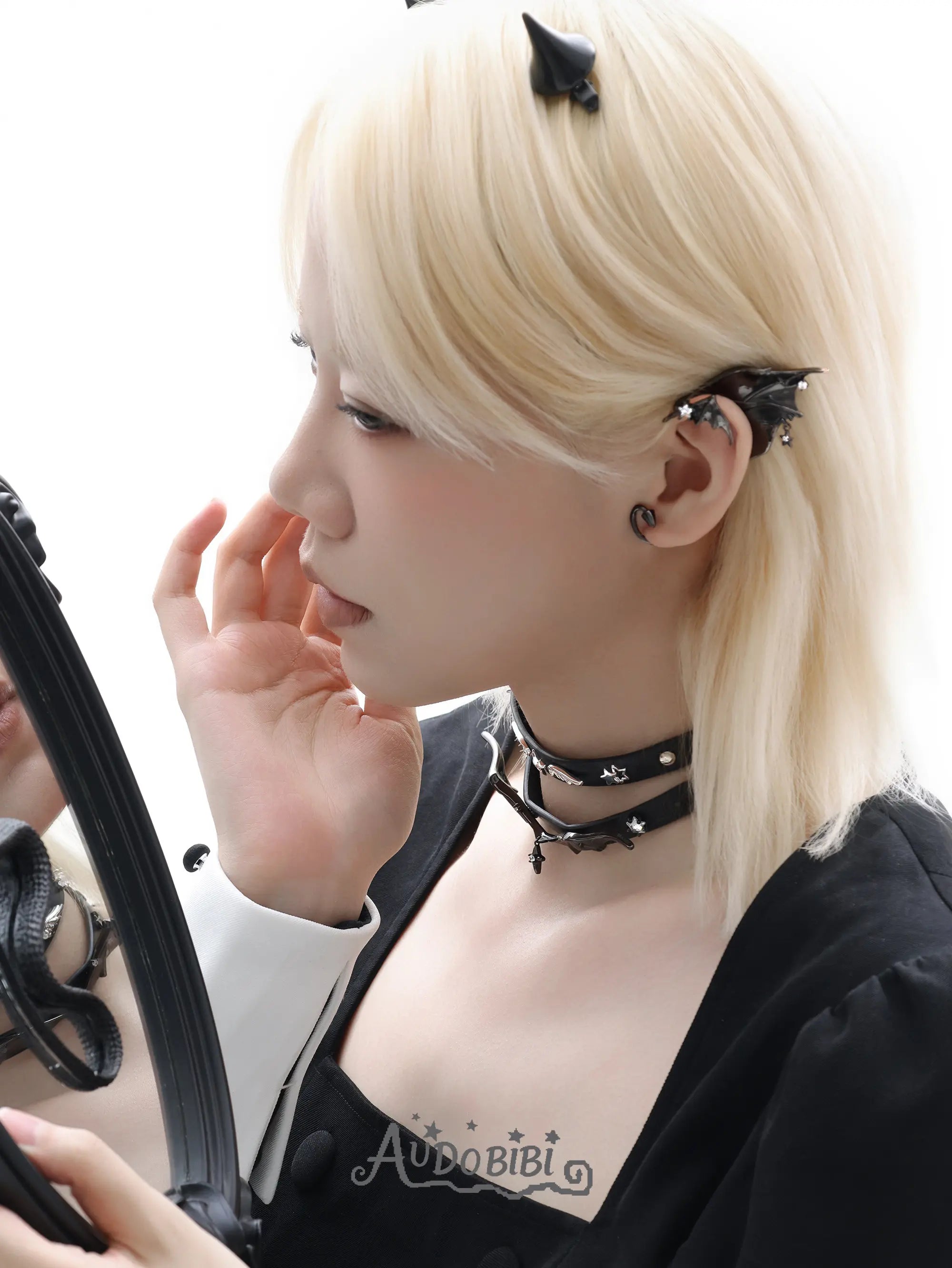 Black bat-wing ear cuff, worn with other jewelry in a model portrait.