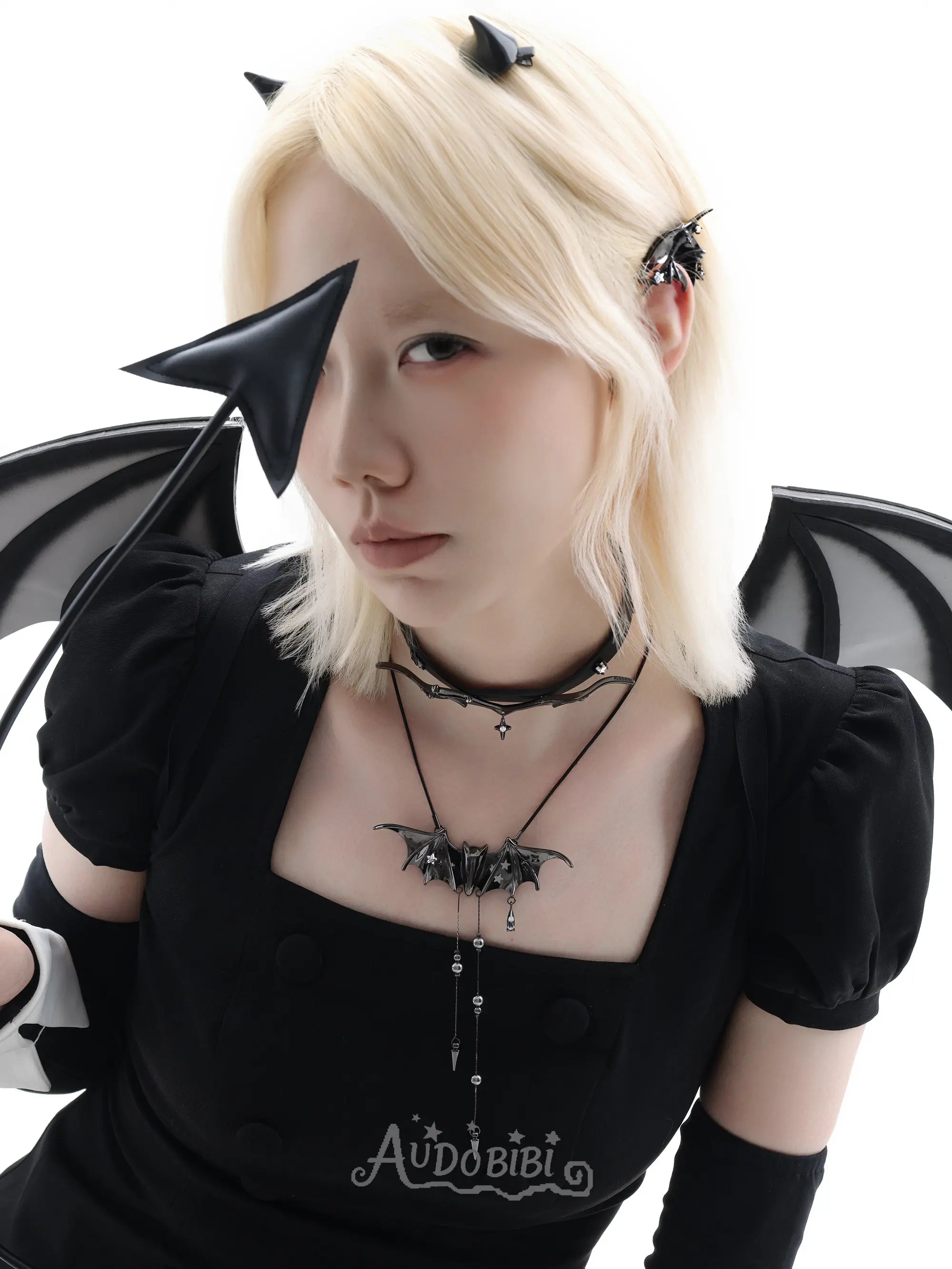 Black bat-wing pendant necklace, worn with other jewelry in a model portrait.
